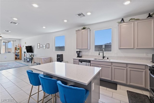 kitchen featuring a breakfast bar, visible vents, gray cabinetry, and a sink