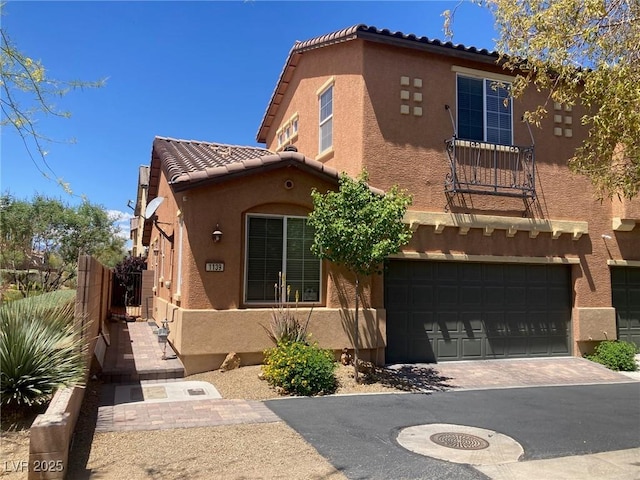 view of front of home featuring an attached garage, stucco siding, a tiled roof, and driveway