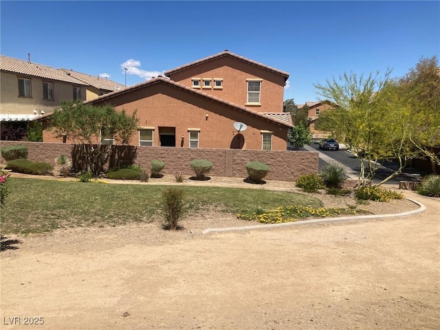 view of side of home featuring stucco siding, a tile roof, and fence