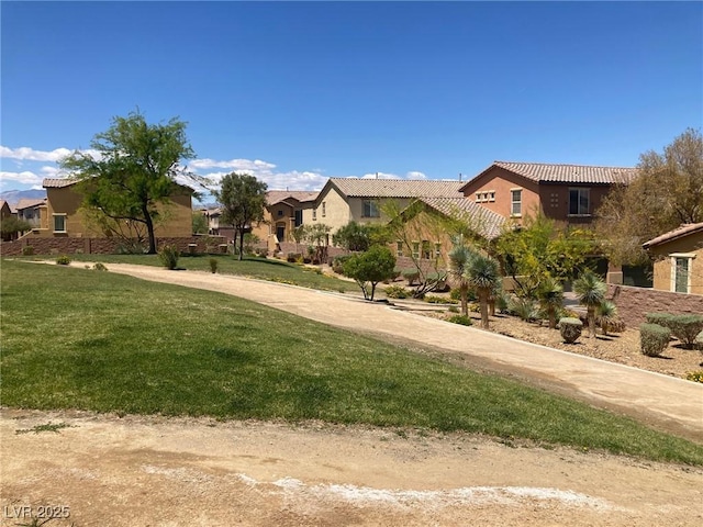 view of front of property featuring a residential view, a tiled roof, stucco siding, and a front yard
