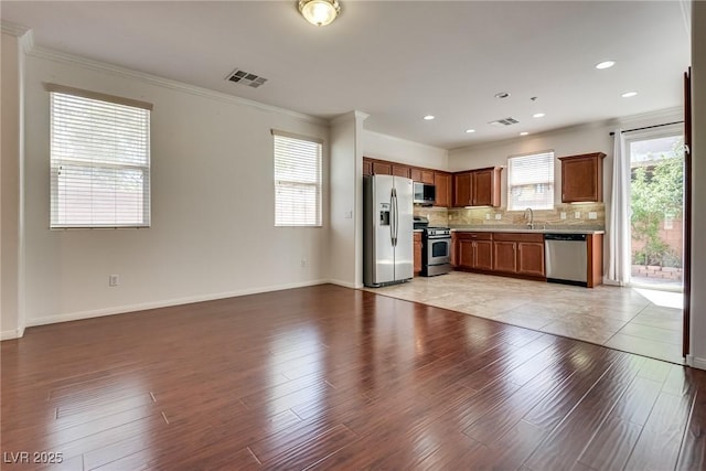 1139 Via Partito, Henderson, NV 89052 - kitchen featuring appliances with stainless steel finishes, a sink, light wood-style flooring, backsplash, and ornamental molding
