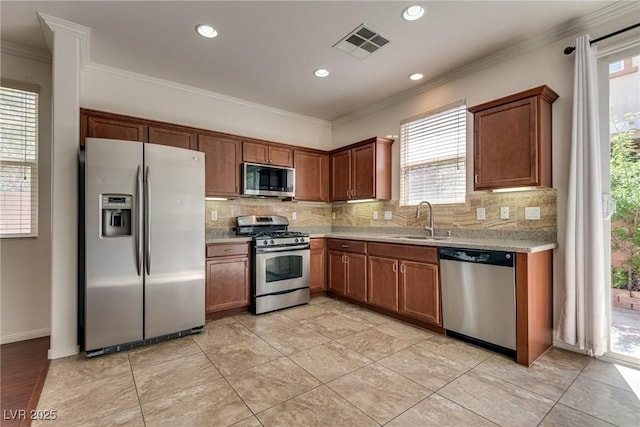 1139 Via Partito, Henderson, NV 89052 - kitchen featuring stainless steel appliances, a sink, backsplash, ornamental molding, and brown cabinetry