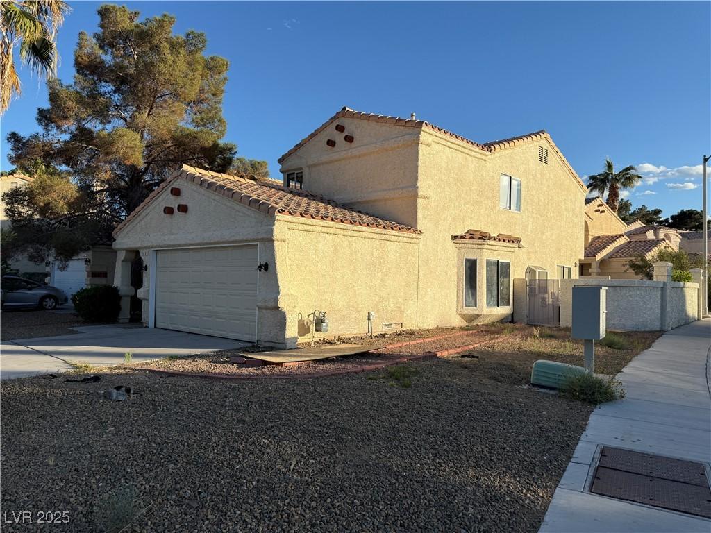 2821 Willow Wind Ct, Las Vegas, NV 89117 - view of home's exterior with driveway, a tile roof, fence, an attached garage, and stucco siding