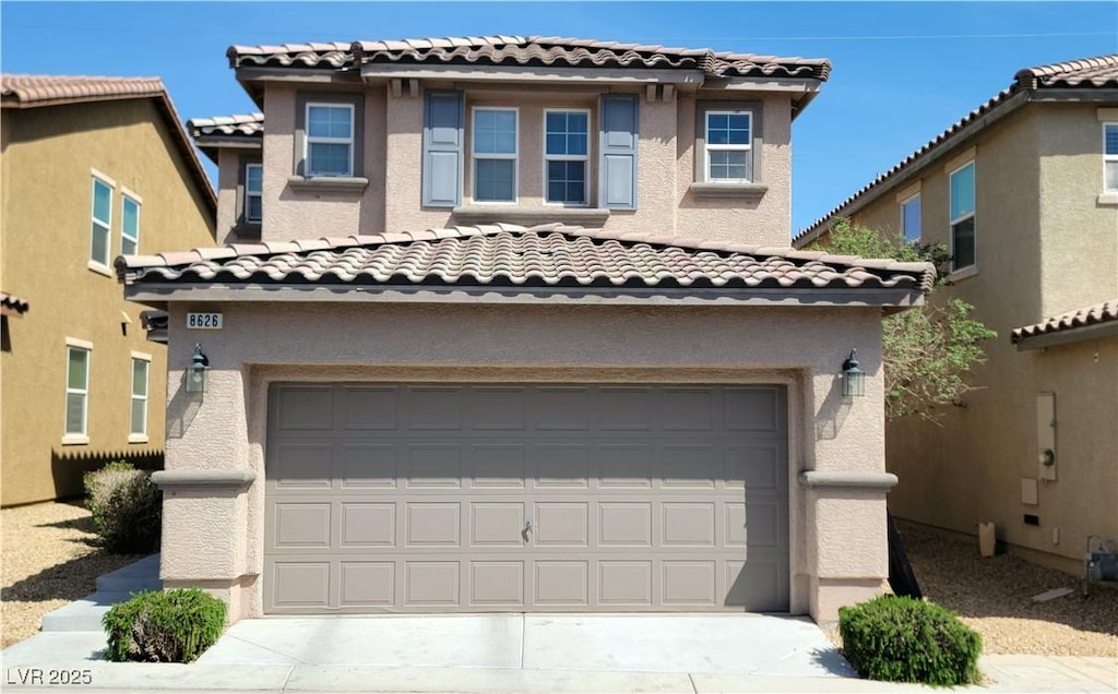 mediterranean / spanish-style house with an attached garage, stucco siding, and a tile roof