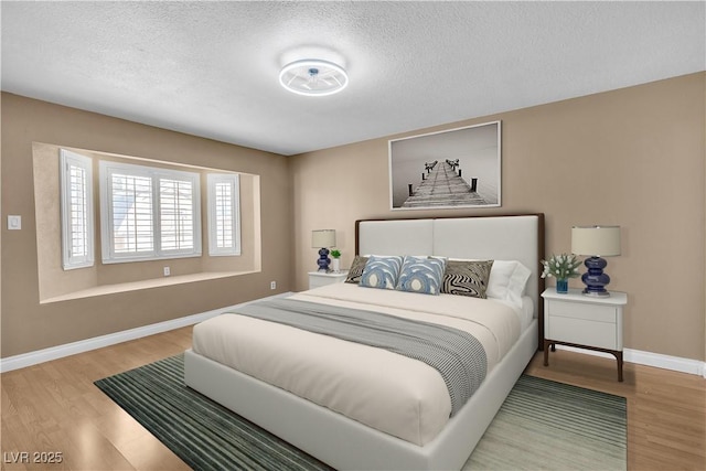 bedroom with a textured ceiling, baseboards, and wood finished floors