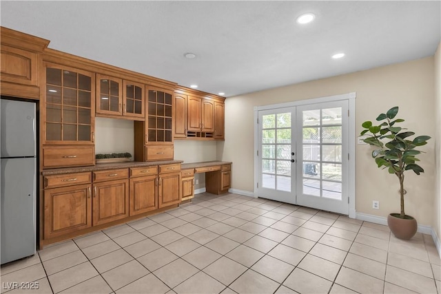 kitchen featuring baseboards, freestanding refrigerator, built in study area, and recessed lighting