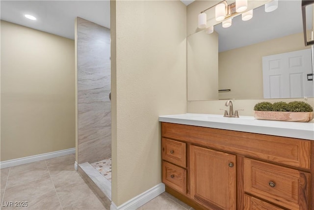 bathroom with vanity, baseboards, tile patterned floors, and tiled shower