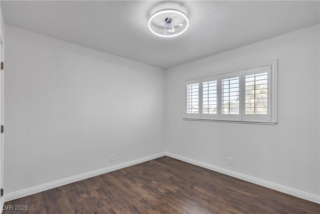 unfurnished room with dark wood-style flooring and baseboards