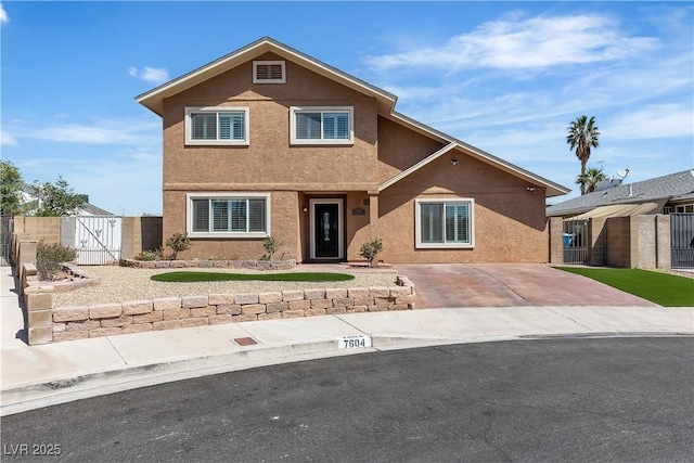 traditional-style home featuring fence, a gate, and stucco siding