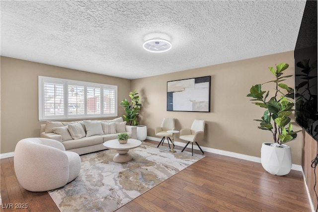 living room with baseboards, a textured ceiling, and hardwood / wood-style floors