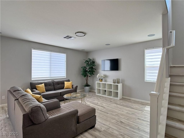 living area with baseboards, visible vents, stairway, and light wood-style floors