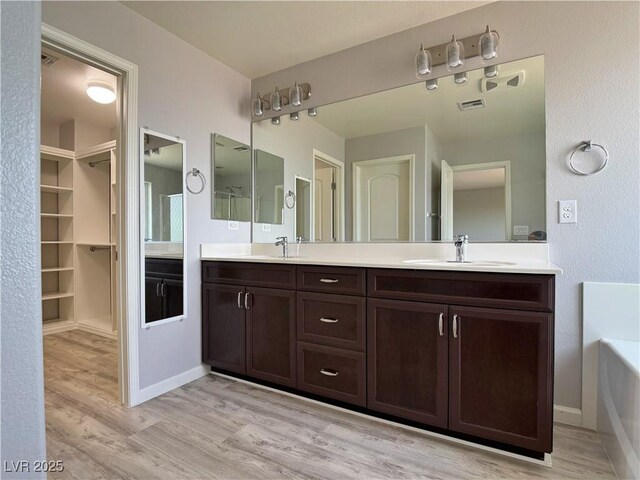 bathroom with double vanity, a sink, and wood finished floors