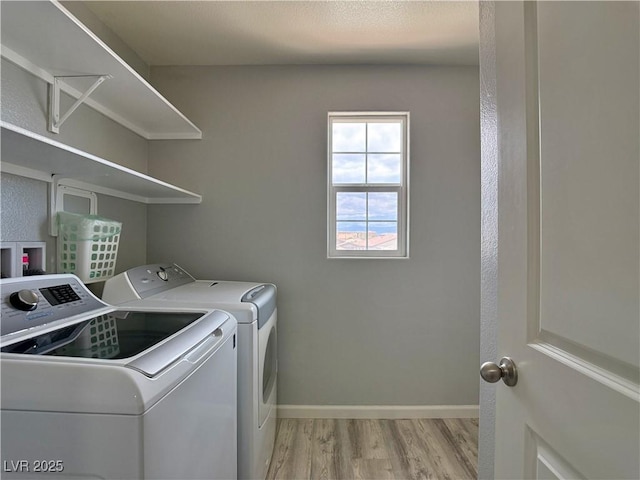 laundry area with baseboards, laundry area, light wood finished floors, and washer and clothes dryer