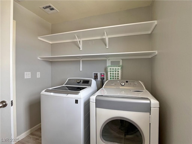 clothes washing area featuring laundry area, independent washer and dryer, visible vents, wood finished floors, and baseboards