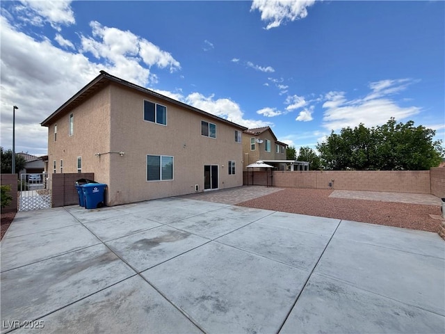 back of house with a fenced backyard, a patio area, and stucco siding