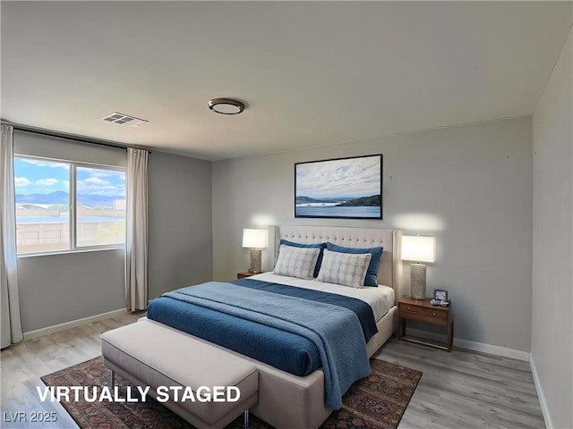bedroom with baseboards, light wood finished floors, and visible vents