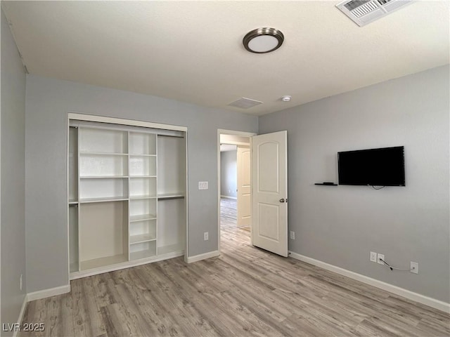 unfurnished bedroom featuring visible vents, baseboards, wood finished floors, and a closet