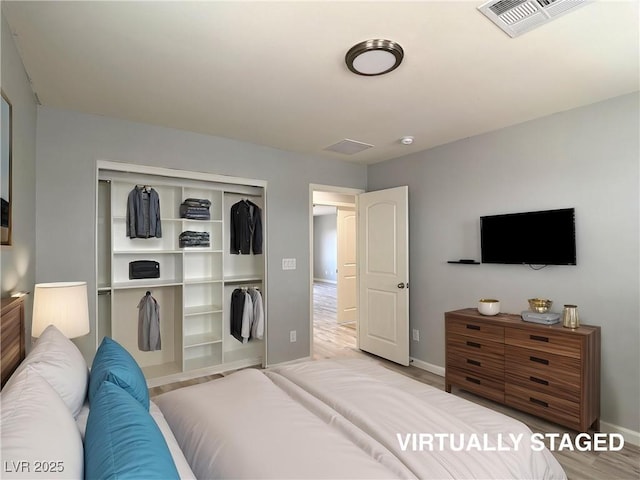 bedroom featuring baseboards, a closet, wood finished floors, and visible vents