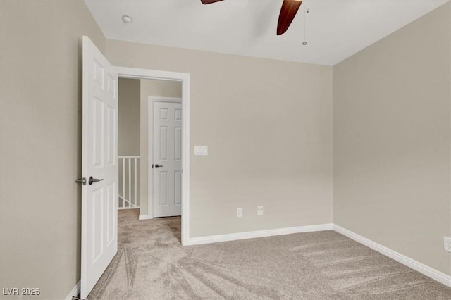 carpeted spare room with ceiling fan and baseboards
