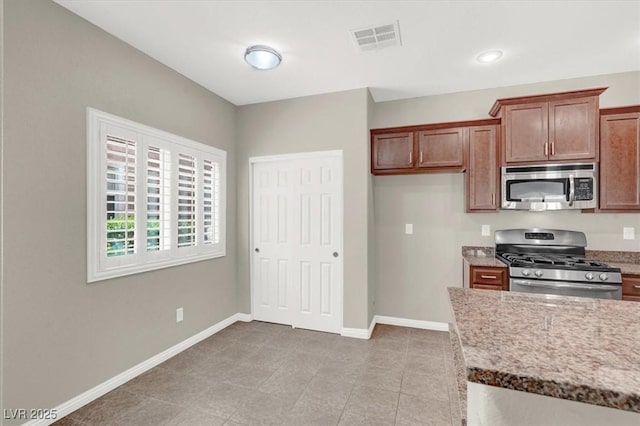 kitchen featuring baseboards, light stone countertops, stainless steel appliances, and visible vents