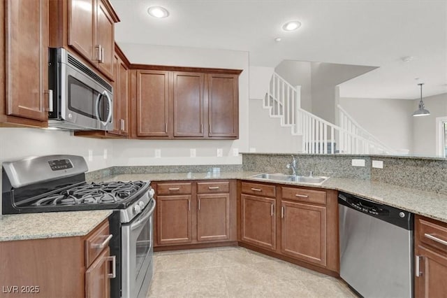 kitchen with brown cabinetry, appliances with stainless steel finishes, light stone countertops, a sink, and light tile patterned flooring