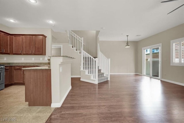 kitchen featuring baseboards, a peninsula, open floor plan, light wood-style floors, and recessed lighting