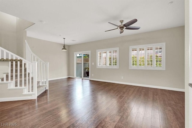 unfurnished living room with a ceiling fan, stairs, wood finished floors, and a wealth of natural light