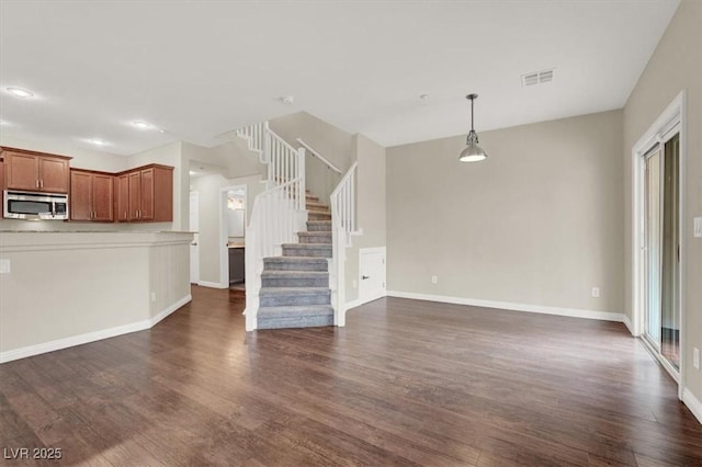 unfurnished living room featuring dark wood finished floors, baseboards, stairs, and visible vents