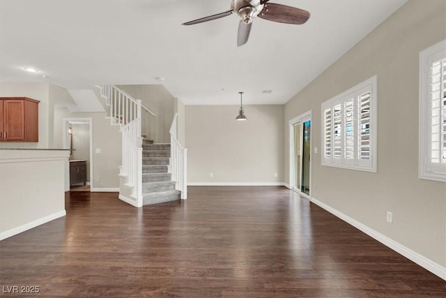 unfurnished living room featuring baseboards, ceiling fan, dark wood-style flooring, and stairs