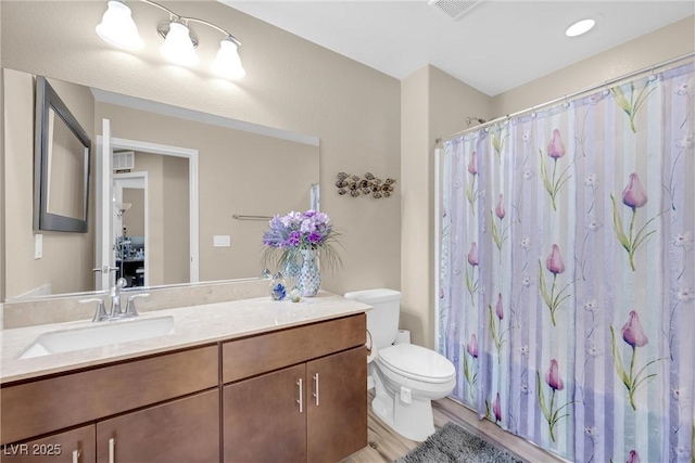 bathroom featuring vanity, visible vents, wood finished floors, toilet, and a shower with shower curtain