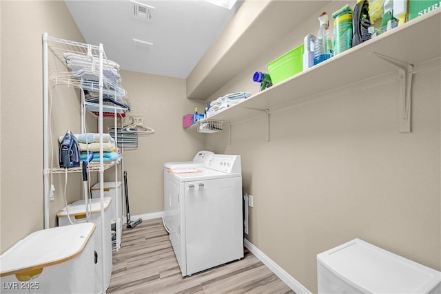 washroom with laundry area, visible vents, washing machine and dryer, baseboards, and light wood finished floors