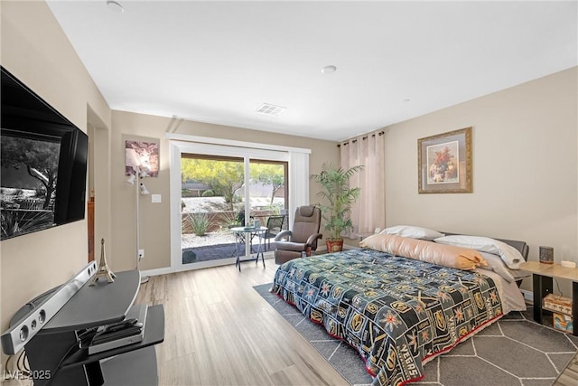 bedroom with access to outside, baseboards, wood finished floors, and visible vents