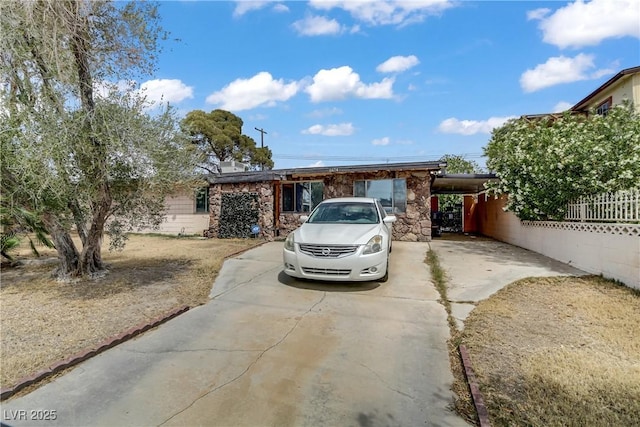 ranch-style house with fence, driveway, and stone siding