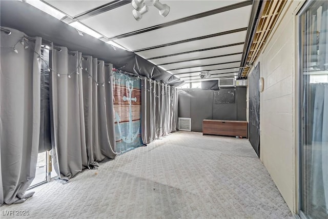 basement with carpet flooring, concrete block wall, visible vents, and plenty of natural light