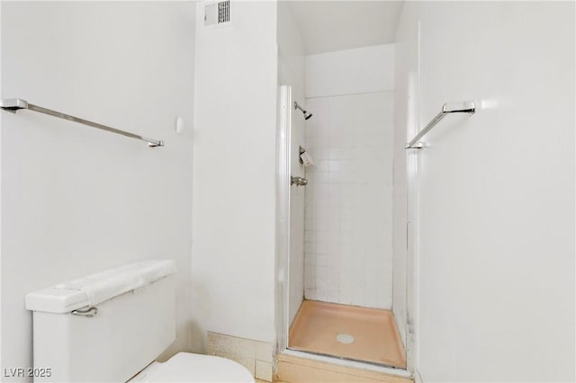 bathroom with toilet, visible vents, and a shower stall