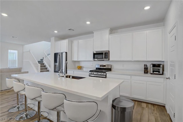 4436 Mural Glen Ct, North Las Vegas, NV 89084 - kitchen featuring a sink, stainless steel appliances, a kitchen bar, visible vents, and a center island with sink
