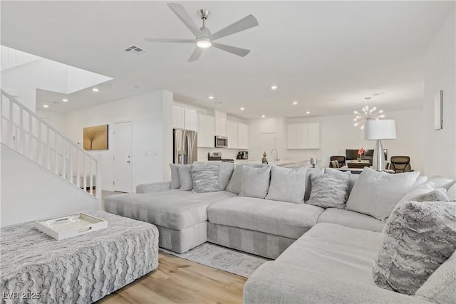 4436 Mural Glen Ct, North Las Vegas, NV 89084 - living room featuring light wood-style floors, a ceiling fan, stairway, recessed lighting, and a chandelier