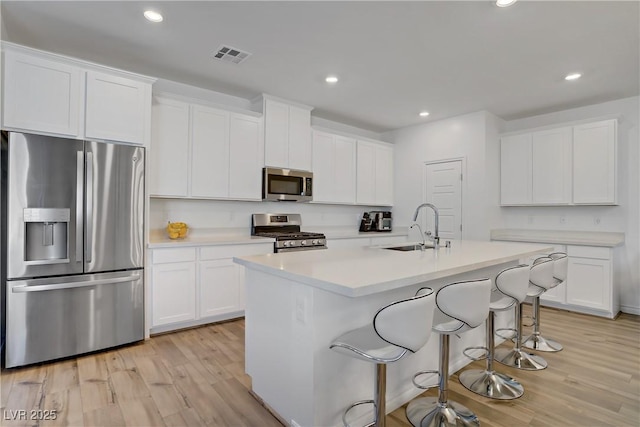 4436 Mural Glen Ct, North Las Vegas, NV 89084 - kitchen featuring stainless steel appliances, light wood-style floors, recessed lighting, a kitchen island with sink, and white cabinets