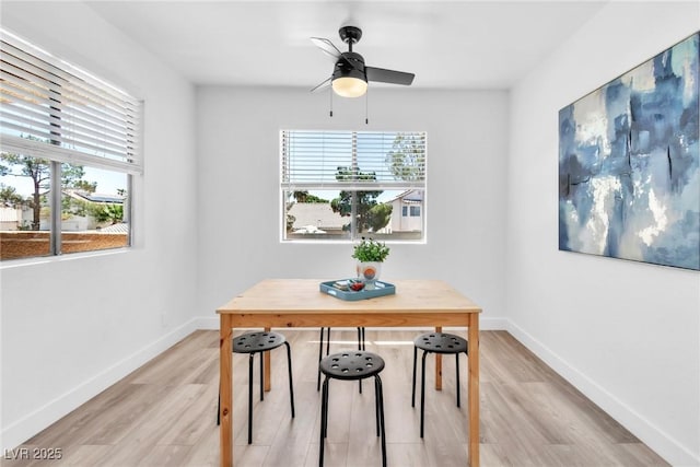 dining space with light wood-style flooring, a ceiling fan, and baseboards