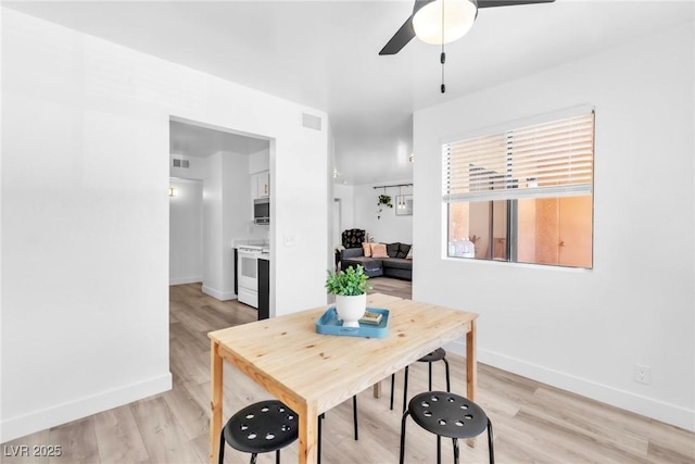 dining space with baseboards, ceiling fan, and light wood-style flooring