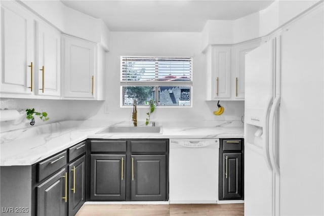 kitchen featuring white appliances, a sink, white cabinets, and light wood finished floors