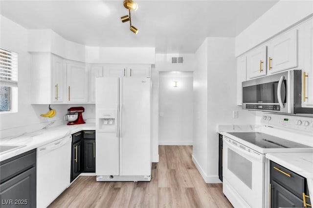 kitchen featuring white appliances, white cabinets, light wood-type flooring, and light stone countertops