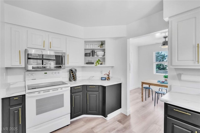 kitchen with stainless steel microwave, electric stove, white cabinets, light wood-type flooring, and open shelves