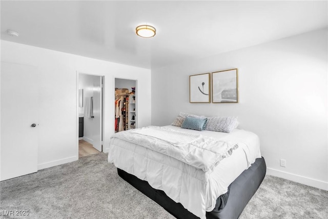 carpeted bedroom featuring baseboards, a walk in closet, and a closet