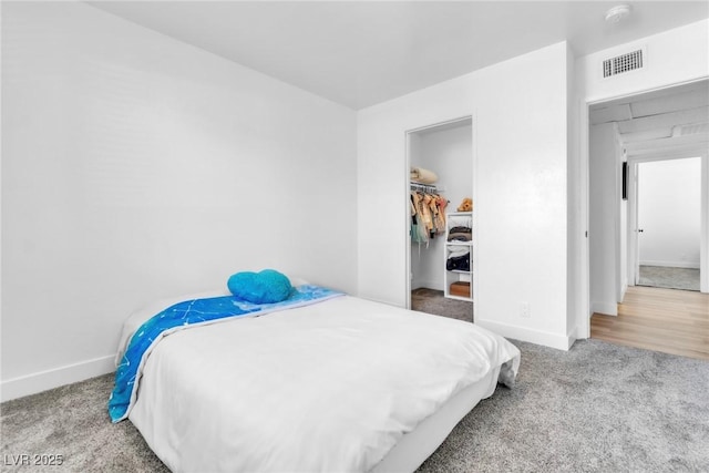 bedroom with baseboards, carpet, and a walk in closet