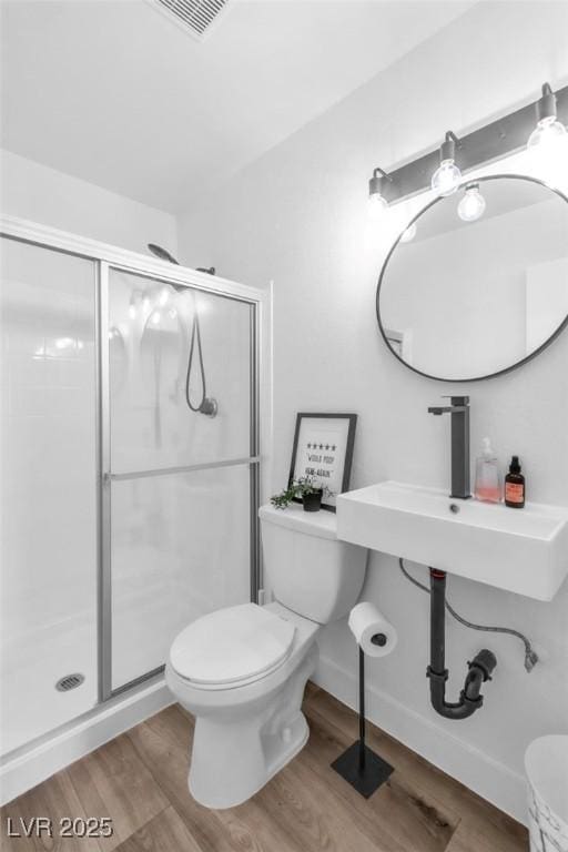 full bath featuring wood finished floors, toilet, and a stall shower