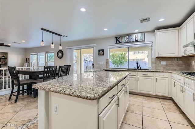 kitchen featuring a kitchen island, recessed lighting, visible vents, and a sink