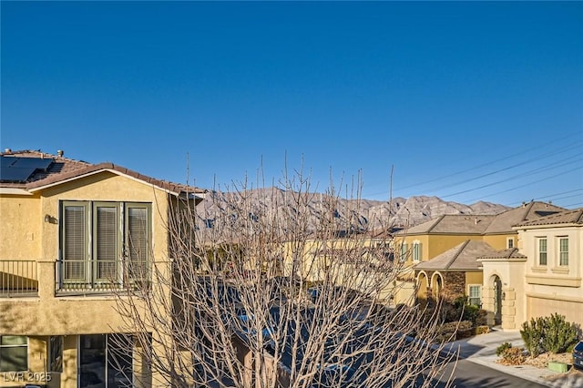 view of property exterior featuring a mountain view, stucco siding, and a balcony