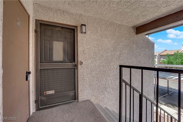 property entrance with a balcony and stucco siding