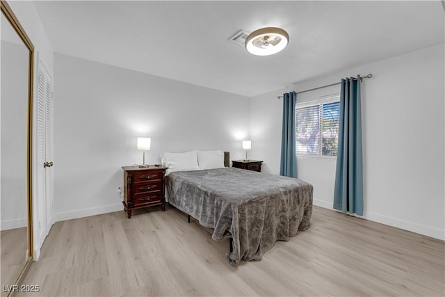 bedroom with baseboards, light wood finished floors, and visible vents